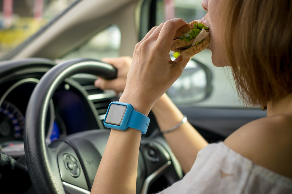 Female driver eating while operating vehicle – common cause of distracted driving accidents in Florida