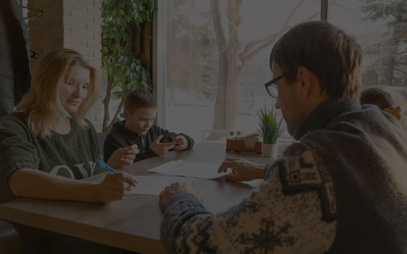 Couple signing custody agreement with child playing handheld game